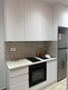 una cocina con armarios blancos y un aparato negro en 3A Apartments 3, en Durrës