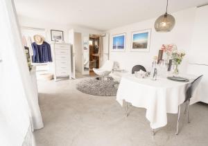 a white dining room with a white table and chairs at Stuga Glommen 2 bed cottage by the sea in Glommen