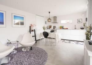 a kitchen and dining room with white cabinets and a table at Stuga Glommen 2 bed cottage by the sea in Glommen +8 photos