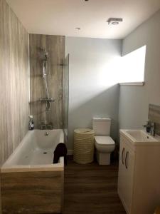 a bathroom with a tub and a toilet and a sink at Cosy country cottage beside Ancient Woodlands in Paxton +8 photos