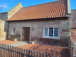 a brick house with a fence in front of it at Cosy country cottage beside Ancient Woodlands in Paxton
