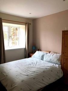 a bedroom with a large bed with a window at Cosy country cottage beside Ancient Woodlands in Paxton