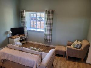 a living room with a couch and chairs and a window at Cosy country cottage beside Ancient Woodlands in Paxton
