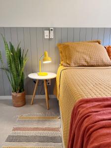 a bedroom with a bed and a yellow lamp on a table at Apê Sunshine| Terraço| Interação com animais in Florianópolis