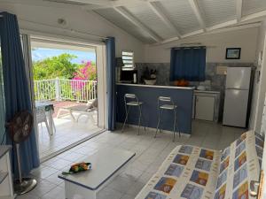a room with a kitchen and a balcony with a table at LE LAGON BLEU, BUNGALOWS Vue sur MER , 350 m de la plage in Sainte-Anne