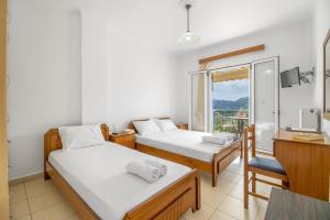 a room with two beds and a desk and a window at Panorama studios 3 in Póndi