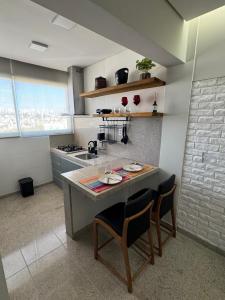 a kitchen with a counter with two chairs and a sink at Raja Vista da Serra in Belo Horizonte