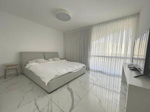 a white bedroom with a bed and a window at 4 חדרים מרווחת 138 מ"ר חניה חינם קרוב לים in Eilat