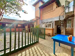 a fence in front of a house with a blue table at Manaca House_ refúgio charmoso_Centro c/ 2 quartos in Ubatuba