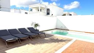 een villa met een zwembad en blauwe stoelen bij Casa Lomas in Playa Blanca