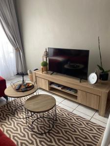 ein Wohnzimmer mit 2 Tischen und einem Flachbild-TV in der Unterkunft AfricaLove on Tiger Suite in Pretoria