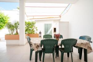 a dining room with a table and green chairs at Villa Camilla by SALENTO OASIS in Porto Cesareo