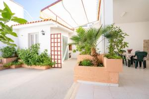 a courtyard with plants and a red door at Villa Camilla by SALENTO OASIS in Porto Cesareo
