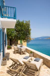 a patio with tables and chairs next to the water at Villa Annouska in Halki