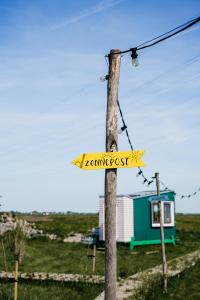 a sign on a wooden pole with a house at Hihahut De Zonnepost in Oud-Ade