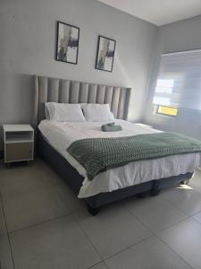 a bedroom with a large bed with a green blanket at WeThusiCBD in Mbabane +4 photos