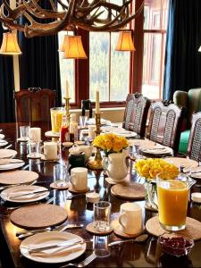 ein großer Holztisch mit Tellern und Gläsern darauf in der Unterkunft Glen Dessary Estate - Fully Catered Bespoke Highland Lodge in Spean Bridge