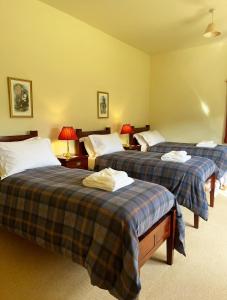 ein Hotelzimmer mit 3 Betten und 2 Lampen in der Unterkunft Glen Dessary Estate - Fully Catered Bespoke Highland Lodge in Spean Bridge + 24 Fotos