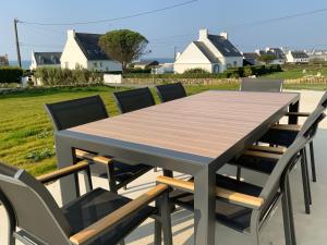 a wooden table with four chairs around it at Maison vue mer prés avec SPA près des plages in Plouhinec
