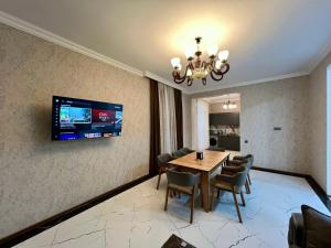 a dining room with a table and chairs and a television at White Terrace Villa in Gabala