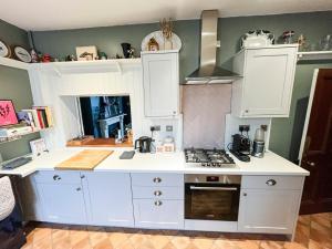 a kitchen with white cabinets and a stove top oven at Boho Family Escape near Dunraven Bay with Sea Views in Southerndown