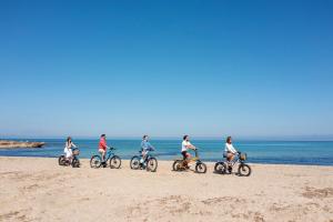 a group of people riding bikes on the beach at Case Vacanza Loria in Castelluzzo