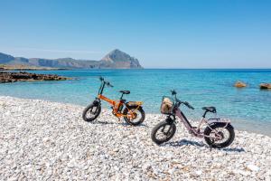 two bikes parked on a rocky beach near the water at Case Vacanza Loria in Castelluzzo