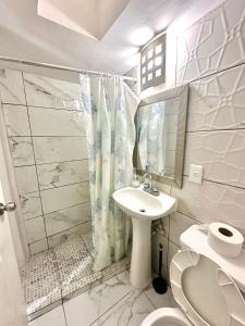 a white bathroom with a sink and a toilet at Departamento Acapulco frente a la playa in Acapulco