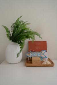 a plant in a white vase next to a book at Strand-chalet Luna - 700 mtr van het strand van Ouddorp in Ouddorp