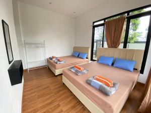 two beds in a room with two windows at Villa Camphills in Gunungpicung