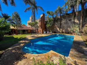 una piscina frente a una casa con palmeras en House with large garden and pool, en Posadas
