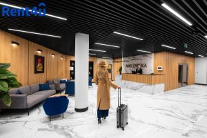 a woman walking through a lobby with a suitcase at Nad Zatoką Aparthotel Deluxe by Rent4You in Olsztyn
