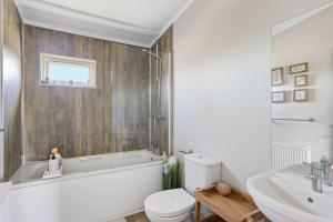 a bathroom with a tub and a toilet and a sink at Bramble Lodge, 12 Roadford Lake Lodges in Broadwoodwidger +19 photos
