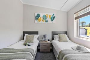 two beds in a room with white walls at Bramble Lodge, 12 Roadford Lake Lodges in Broadwoodwidger