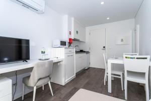 una cucina bianca con una scrivania con TV e sedie di GuestReady - Passal Guesthouse a Ponta Delgada