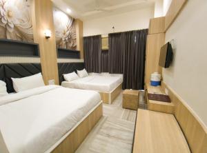 Una habitación de hotel con dos camas y un televisor. en Hotel Jai Palace, en Ajmer 34 fotos más