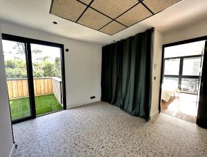 an empty room with green curtains and a balcony at Maison bord de mer Anglet in Anglet +2 photos