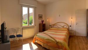 a bedroom with a bed with two chairs and a window at Armonia Affittacamere in San Vicenzo di Galliera