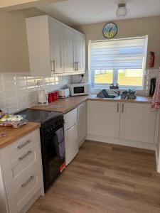 a kitchen with white cabinets and a sink and a window at 63 Bermuda in Hemsby