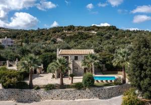 a house with palm trees and a swimming pool at Teacher Cottage in Agia Triada