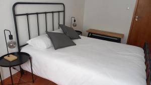 a bedroom with a white bed with two pillows at Várzea Alojamentos Turísticos in Vila Nova de Milfontes