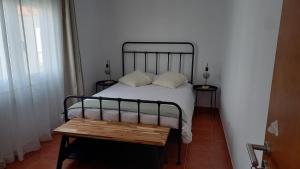 a bedroom with a bed and a wooden table at Várzea Alojamentos Turísticos in Vila Nova de Milfontes
