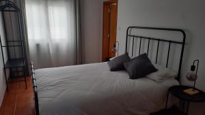 a bedroom with a bed with white sheets and black pillows at Várzea Alojamentos Turísticos in Vila Nova de Milfontes +4 photos