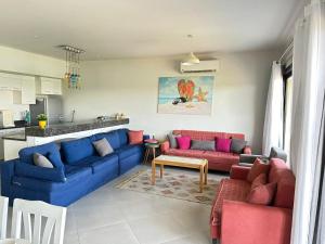 un salon avec des canapés bleus et roses et une cuisine dans l'établissement Apartment at Marassi, à El Alamein