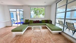 a large living room with a green couch and windows at Cabaña Costa de Oro in San Antero