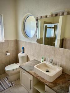 a bathroom with a sink and a toilet and a mirror at Sandy Greens Villa in Swakopmund