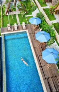 una persona che nuota in una piscina con gli ombrelloni e una persona sdraiata di Villa August Lombok a Selong Belanak