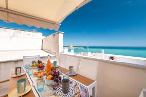 una mesa con comida en el balcón con vistas al océano en Villa Helena by BarbarHouse, en Vieste