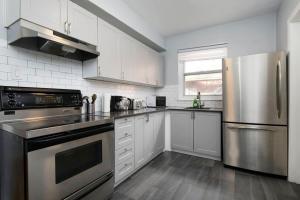 Una cocina con gabinetes blancos y un refrigerador de acero inoxidable. en Awesome 2BR in Montreal, en Montreal