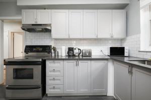 Una cocina con gabinetes blancos y un horno de estufa. en Awesome 2BR in Montreal, en Montreal 10 fotos más